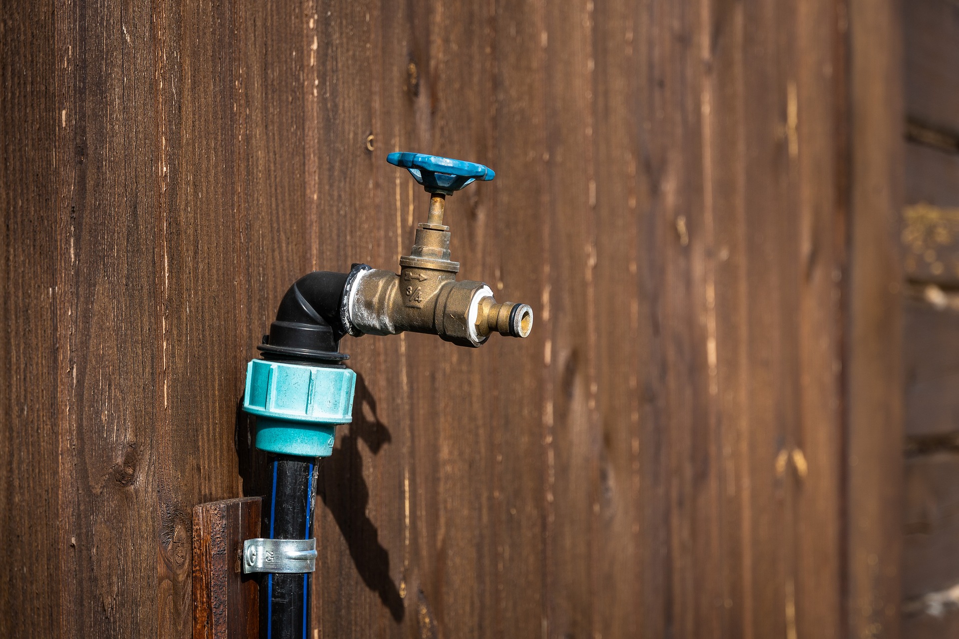 Outdoor tap on wooden wall. Prepare your plumbing for winter